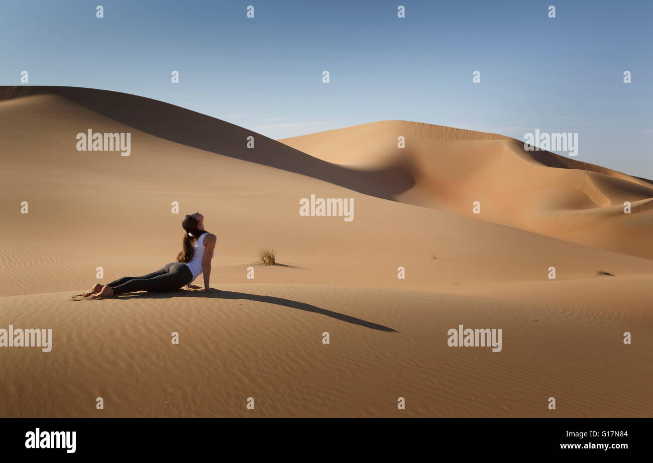 Giovane donna a praticare yoga su una duna di sabbia nel deserto, Abu Dhabi Abu Dhabi Emirato, EMIRATI ARABI UNITI Foto Stock