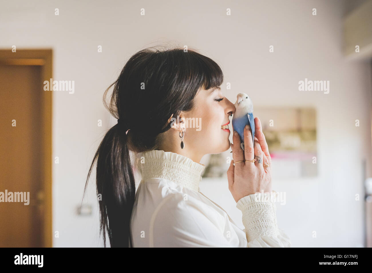 Giovane donna azienda pet bird in ambienti interni Foto Stock