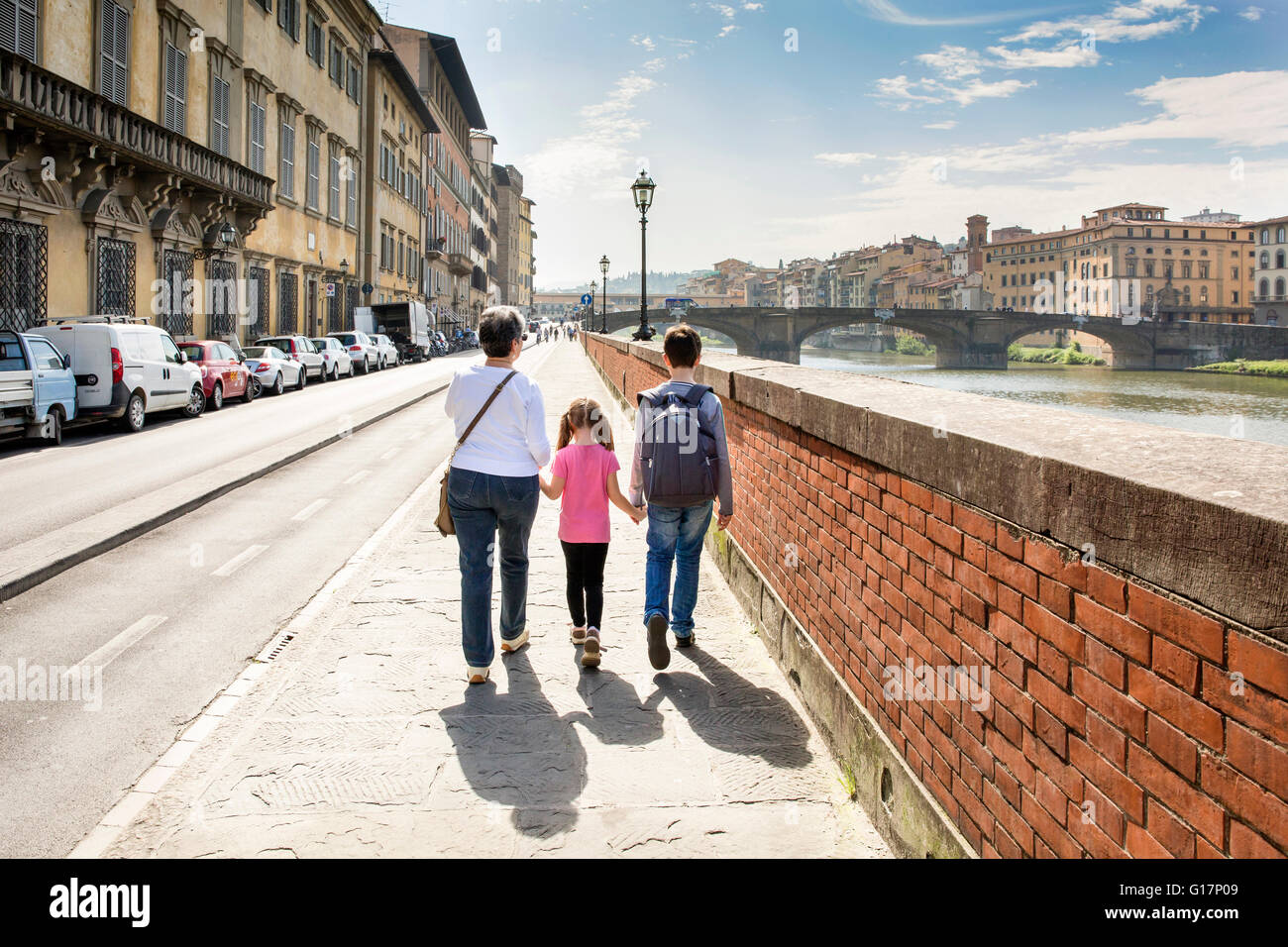 Vista posteriore della donna senior e due nipoti passeggiando attraverso il fiume Arno, Firenze, Italia Foto Stock