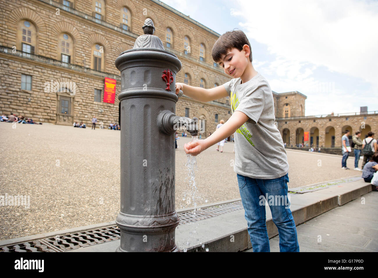 Ragazzo con mano sotto la vecchia pompa acqua, Firenze, Italia Foto Stock