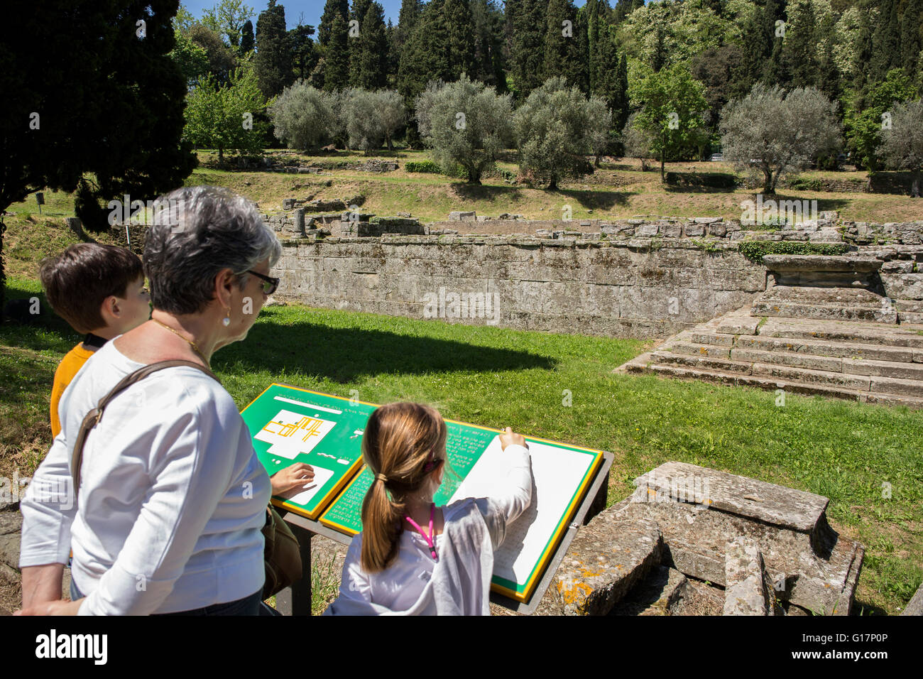 Donna senior e i nipoti guardando rovine informazioni segno, Firenze, Italia Foto Stock