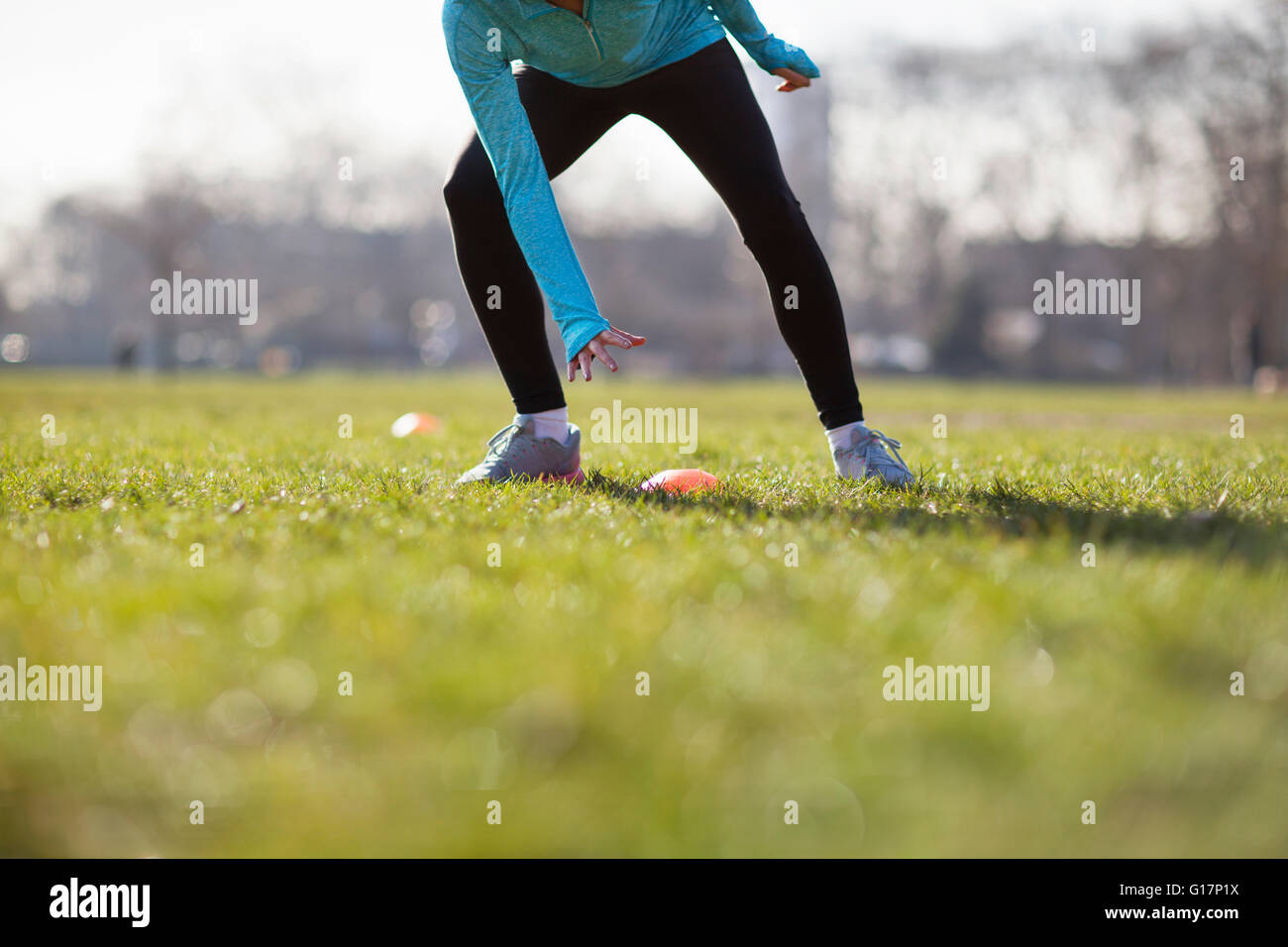 Vita scende vista della giovane donna formazione, toccando il cono marcatore sul campo da gioco Foto Stock