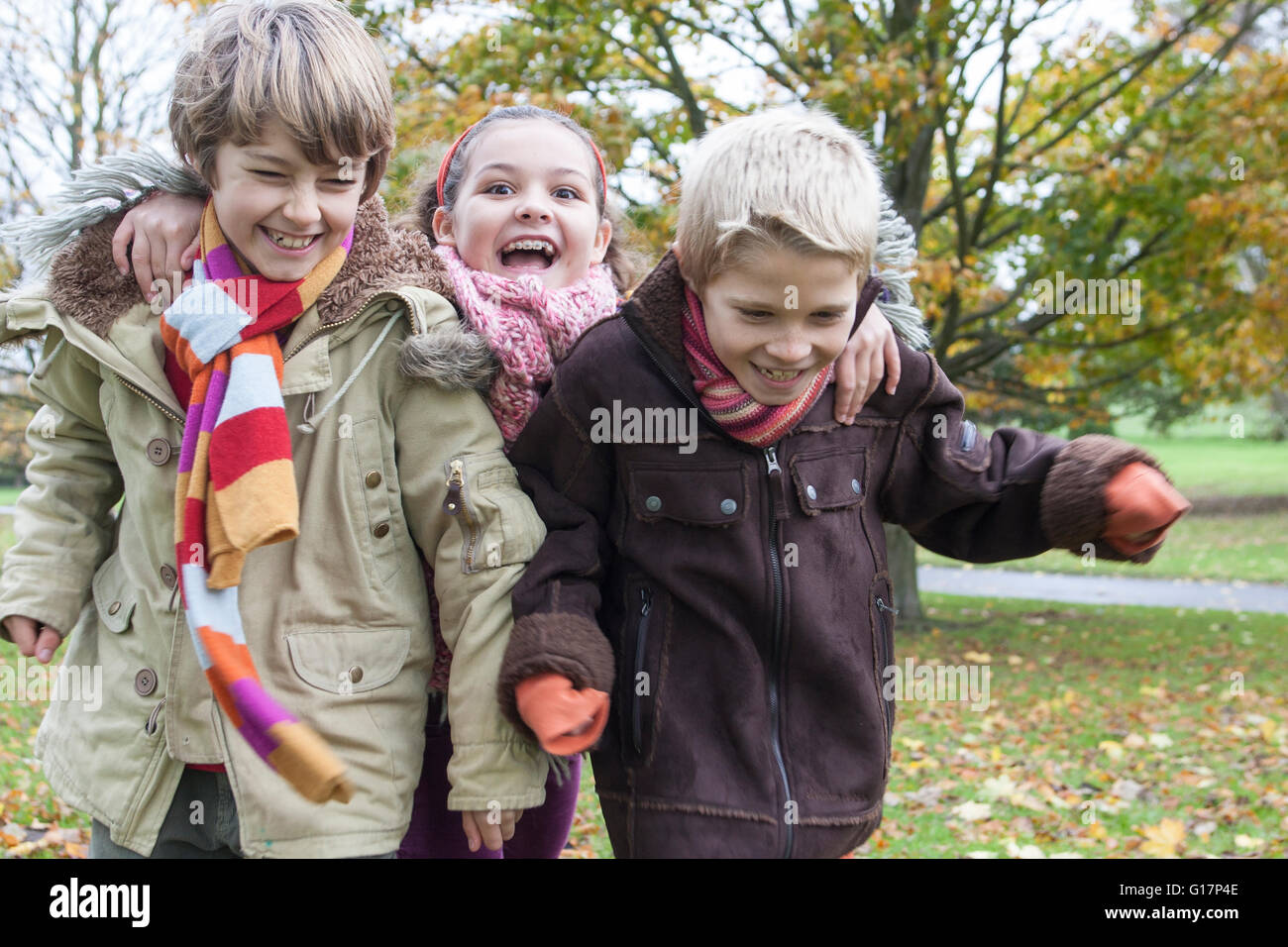 Tre bambini in esecuzione nel parco, ridendo Foto Stock