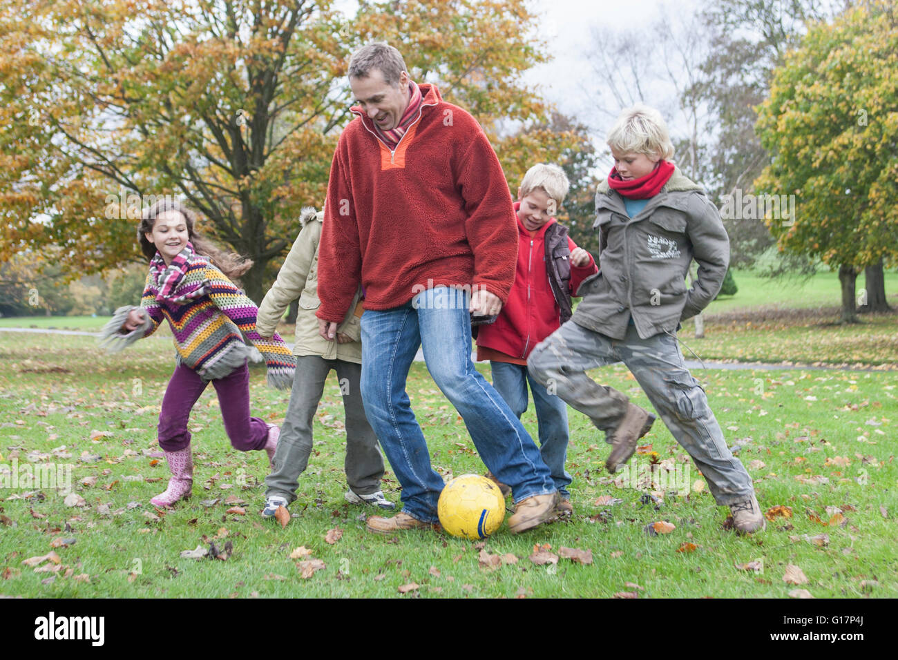 Padre e figli, giocando a calcio in posizione di parcheggio Foto Stock