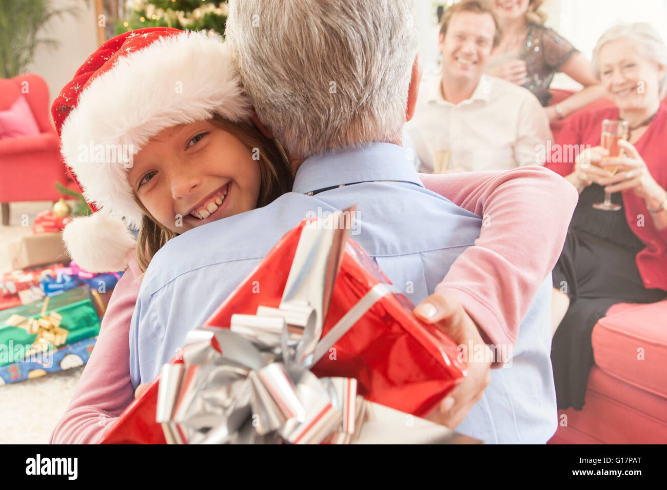 La nipote azienda regalo di Natale abbracciando nonno sorridente Foto Stock