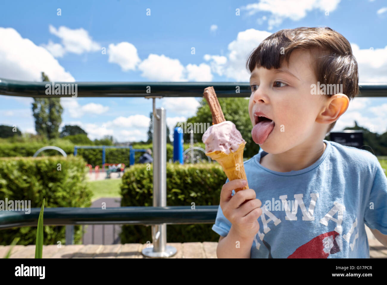 Ragazzo godendo di cono gelato nei pressi di parco giochi, Richmond, Londra Foto Stock