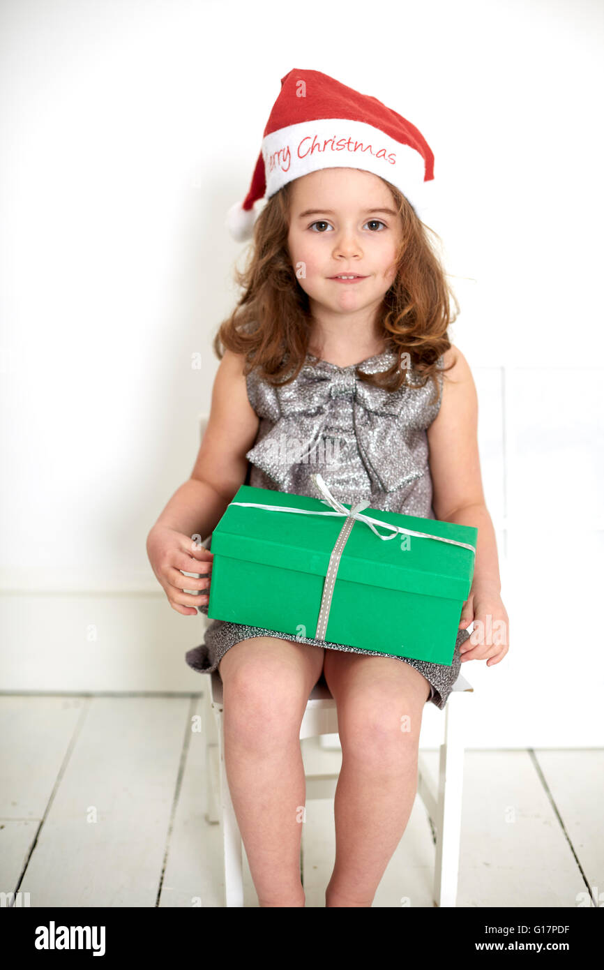 La ragazza di santa hat con un regalo di Natale al giro Foto Stock