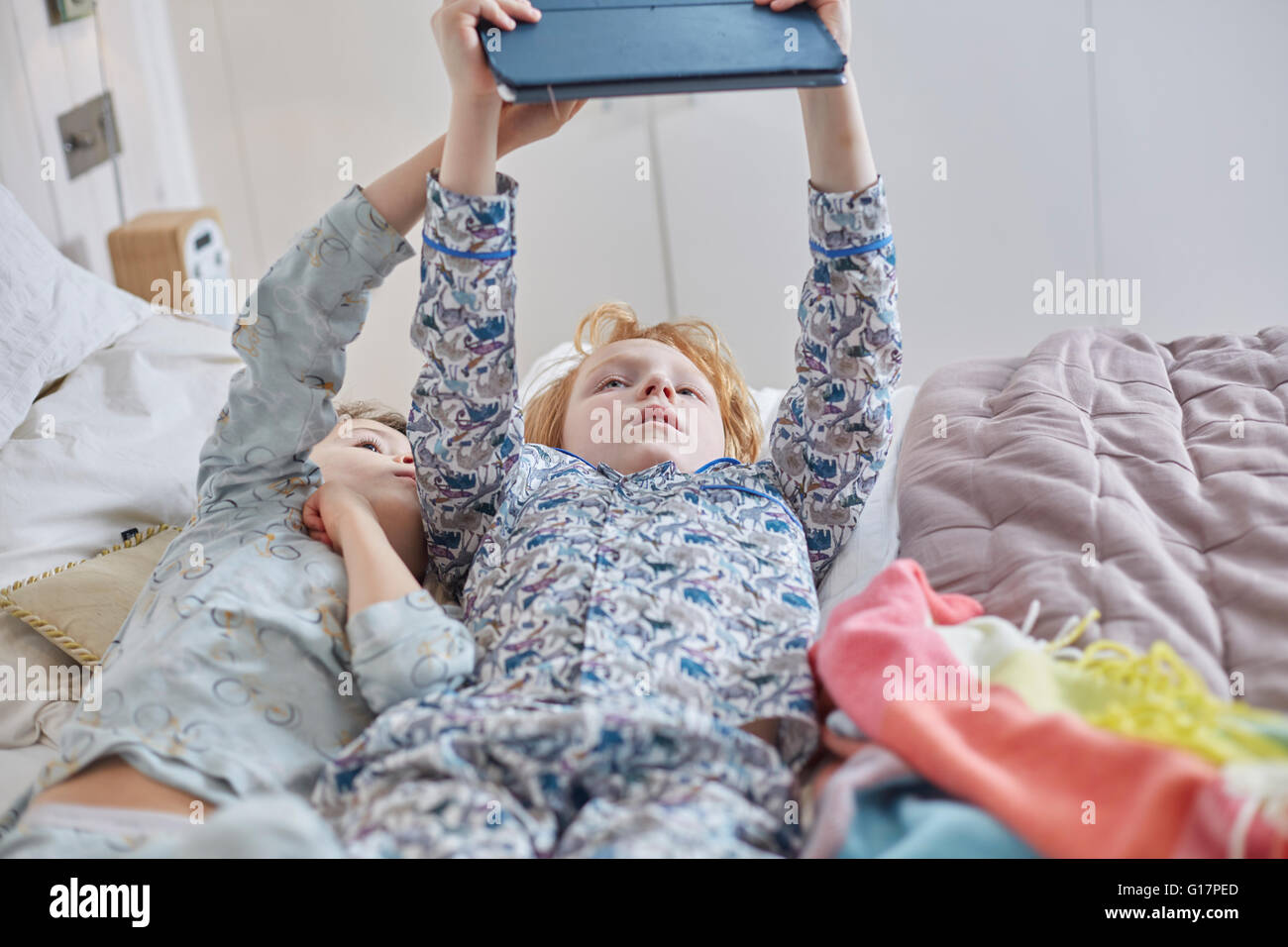 I bambini in pigiama con tavoletta digitale a letto Foto Stock