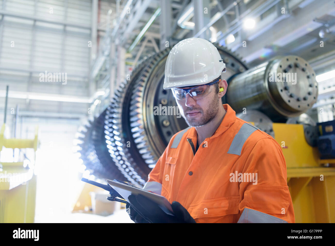 Lavoratore con tavoletta digitale nella parte anteriore della turbina a gas in una centrale elettrica a gas Foto Stock