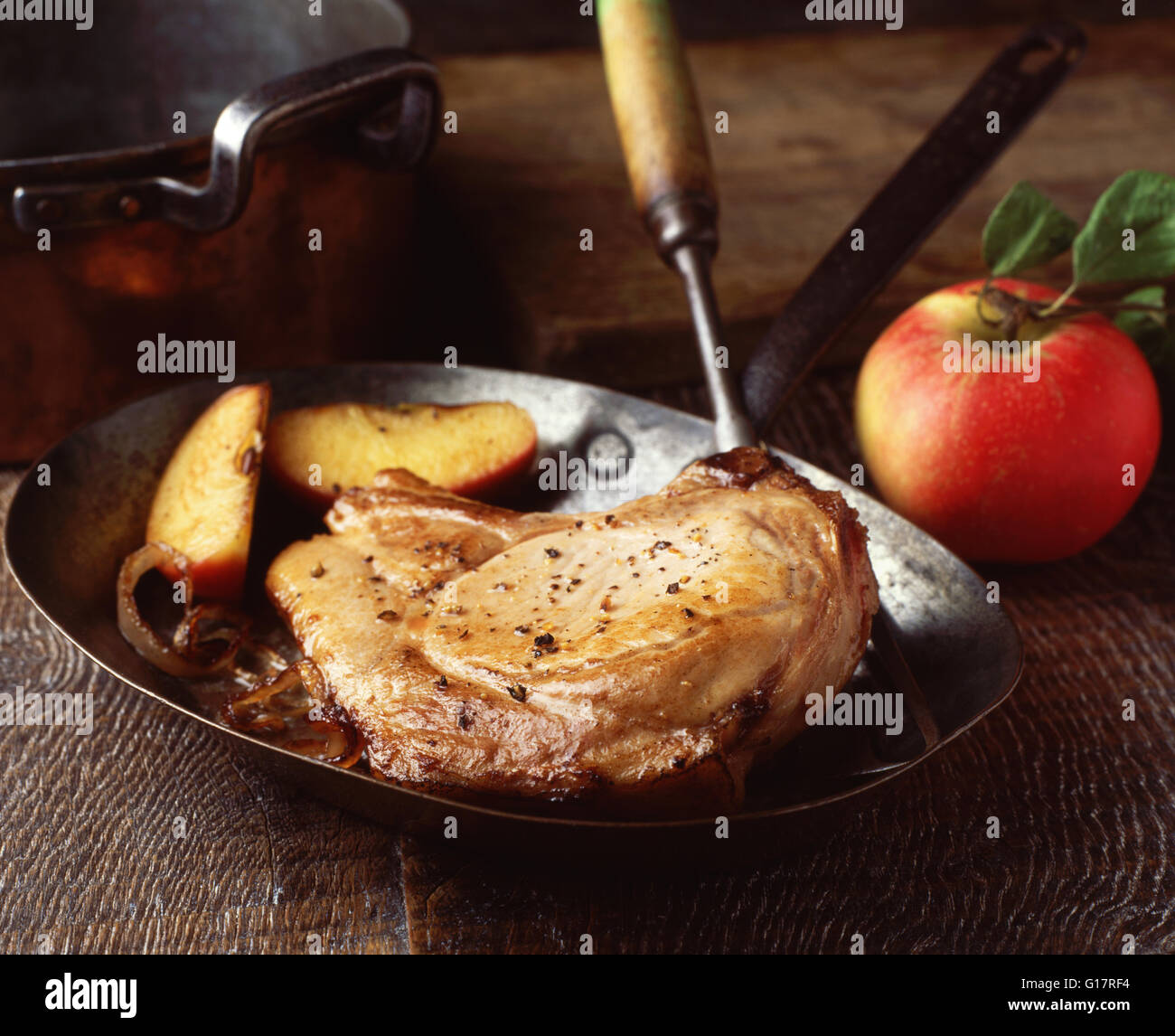 Tritare la carne di maiale saltato con Apple e cipolle vintage in padella Foto Stock