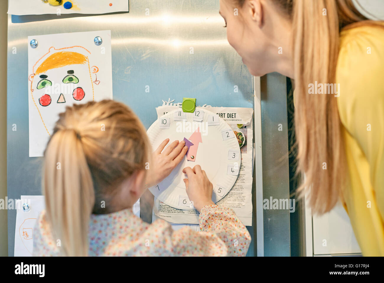Madre figlia di insegnamento al tempo di lettura su carta orologio Foto Stock