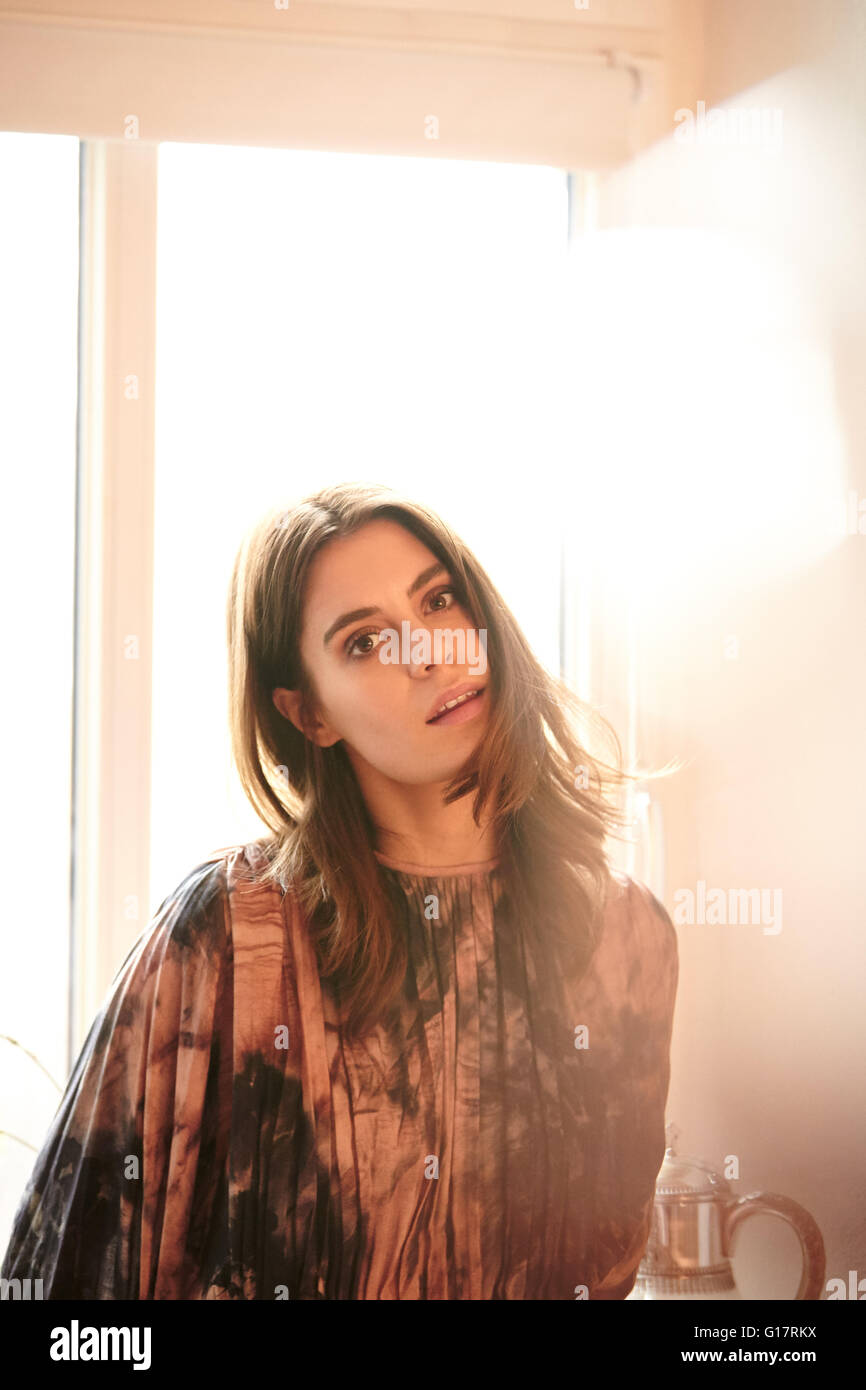 Ritratto di giovane donna di fronte a finestre illuminate dal sole Foto Stock