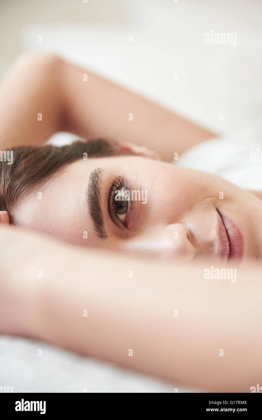 Close up ritratto di giovane e bella donna sdraiata sul letto Foto Stock