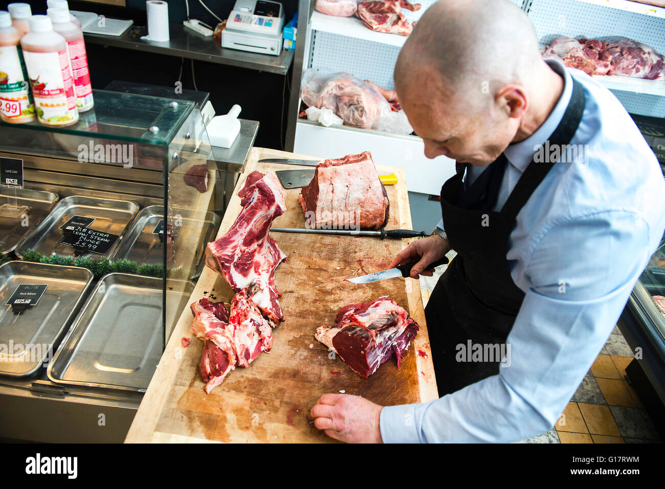 Butcher preparare la carne in macelleria Foto Stock