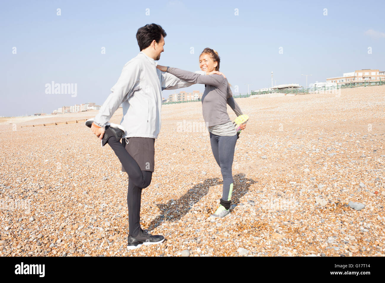 L uomo e la donna la formazione, in piedi su una gamba sola sulla spiaggia di Brighton Foto Stock