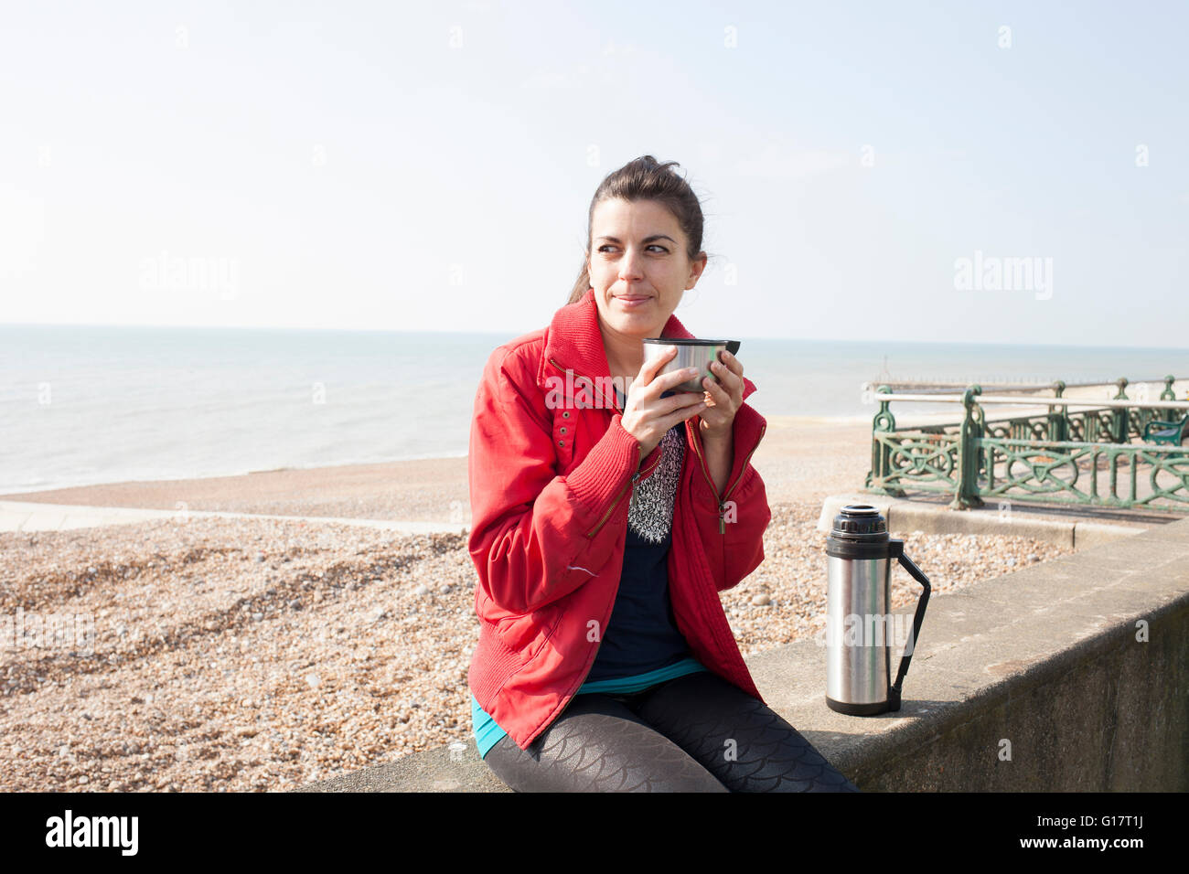 Femminile prendendo una pausa caffè sulla parete presso la spiaggia di Brighton Foto Stock