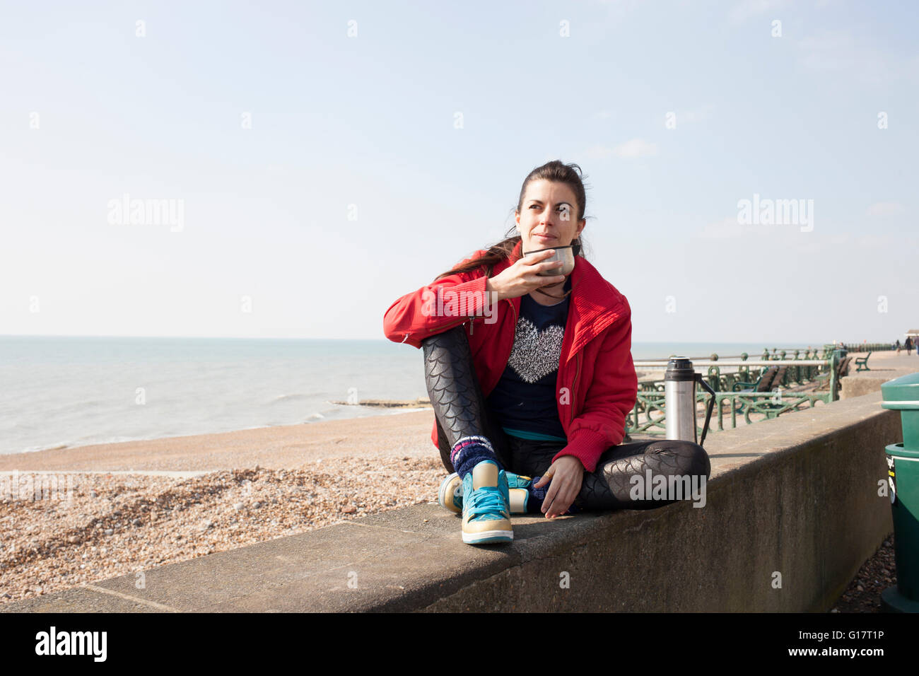 Femminile prendendo una pausa caffè sulla parete presso la spiaggia di Brighton Foto Stock