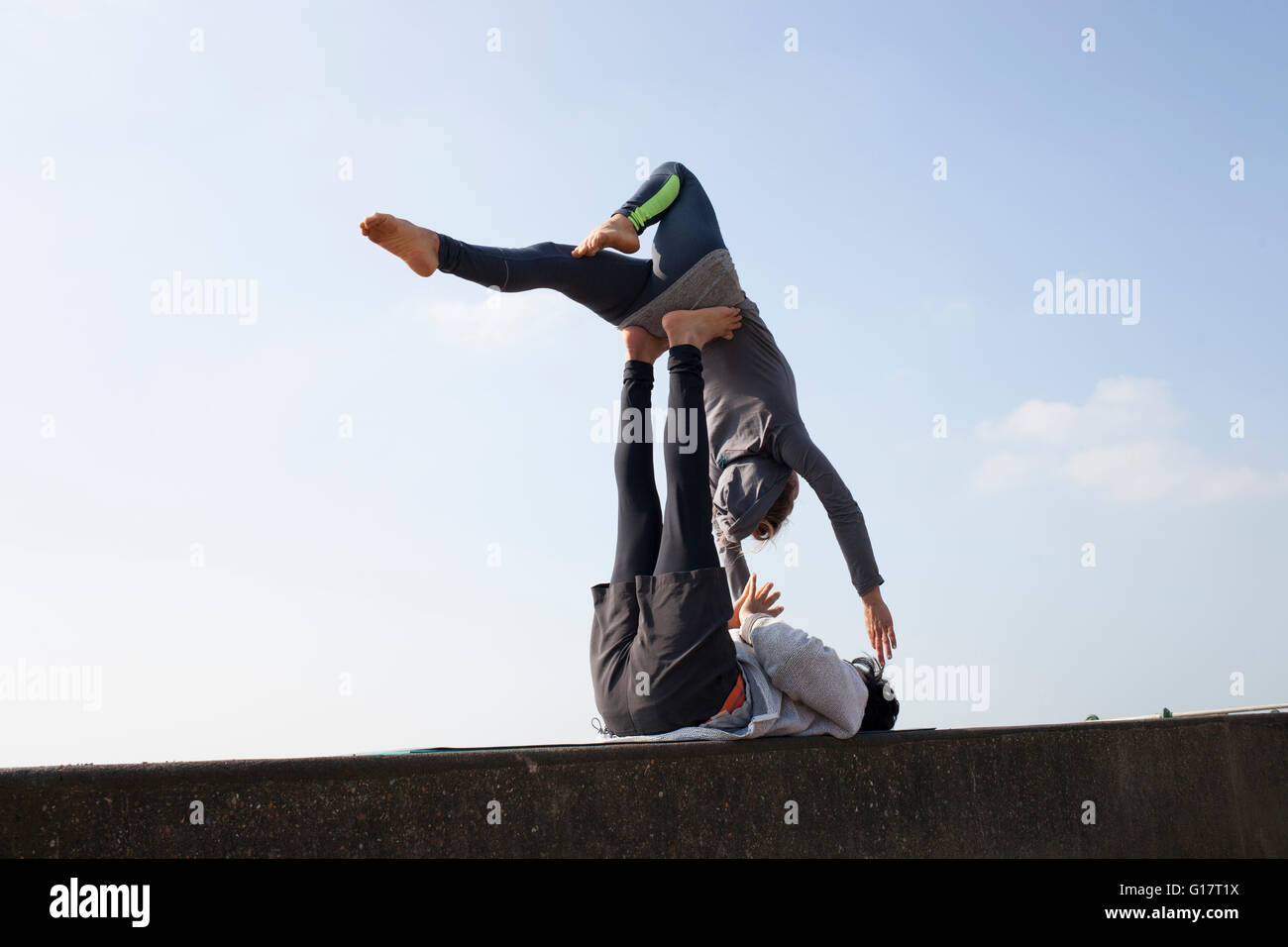 L uomo e la donna pratica yoga acrobatico sul muro contro il cielo blu Foto Stock