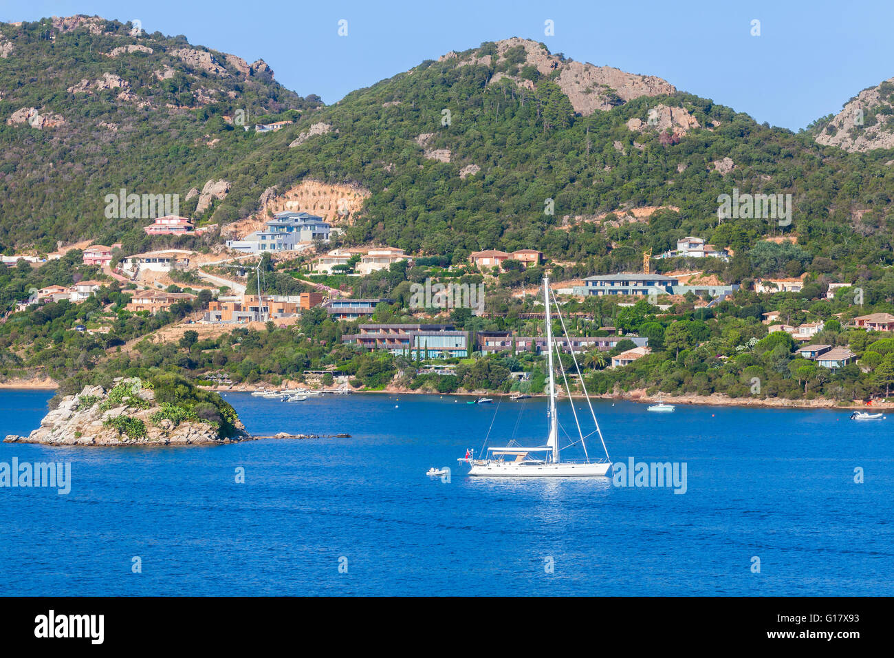 Il paesaggio costiero di Porto-Vecchio bay, Corsica, Francia. Bianco yacht a vela andare vicino alla piccola isola rocciosa Foto Stock