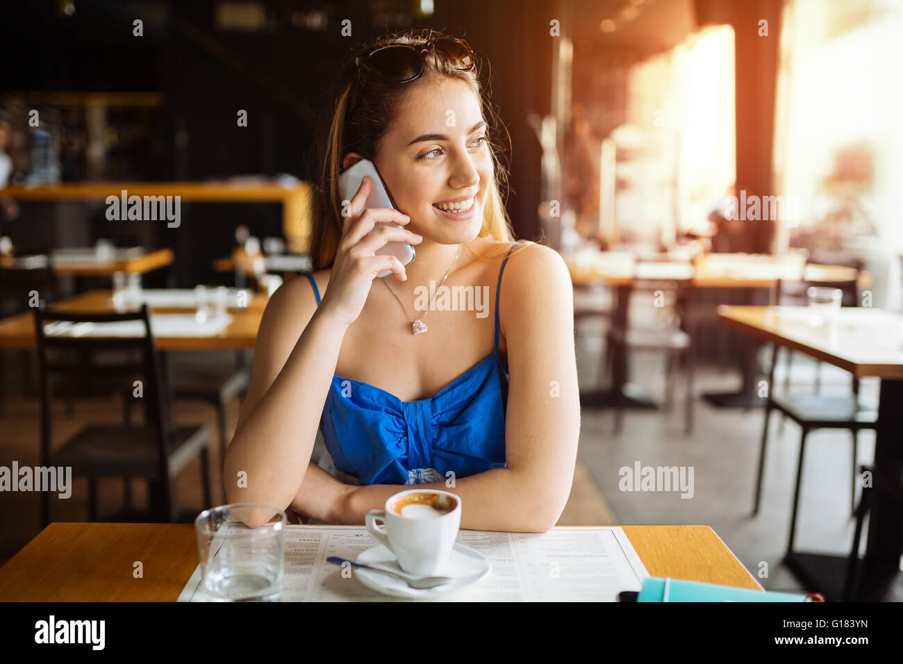Bella donna parlando al cellulare e di bere il caffè Foto Stock