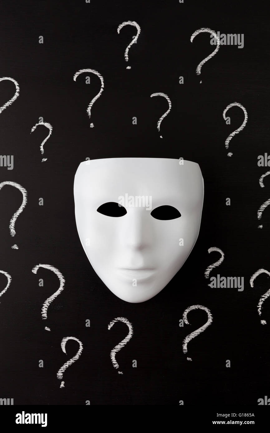 Maschera bianca su sfondo nero con disegnati a mano di Chalk dei punti interrogativi. Chi sono Io ? Il concetto di identità. L'immagine verticale. Foto Stock