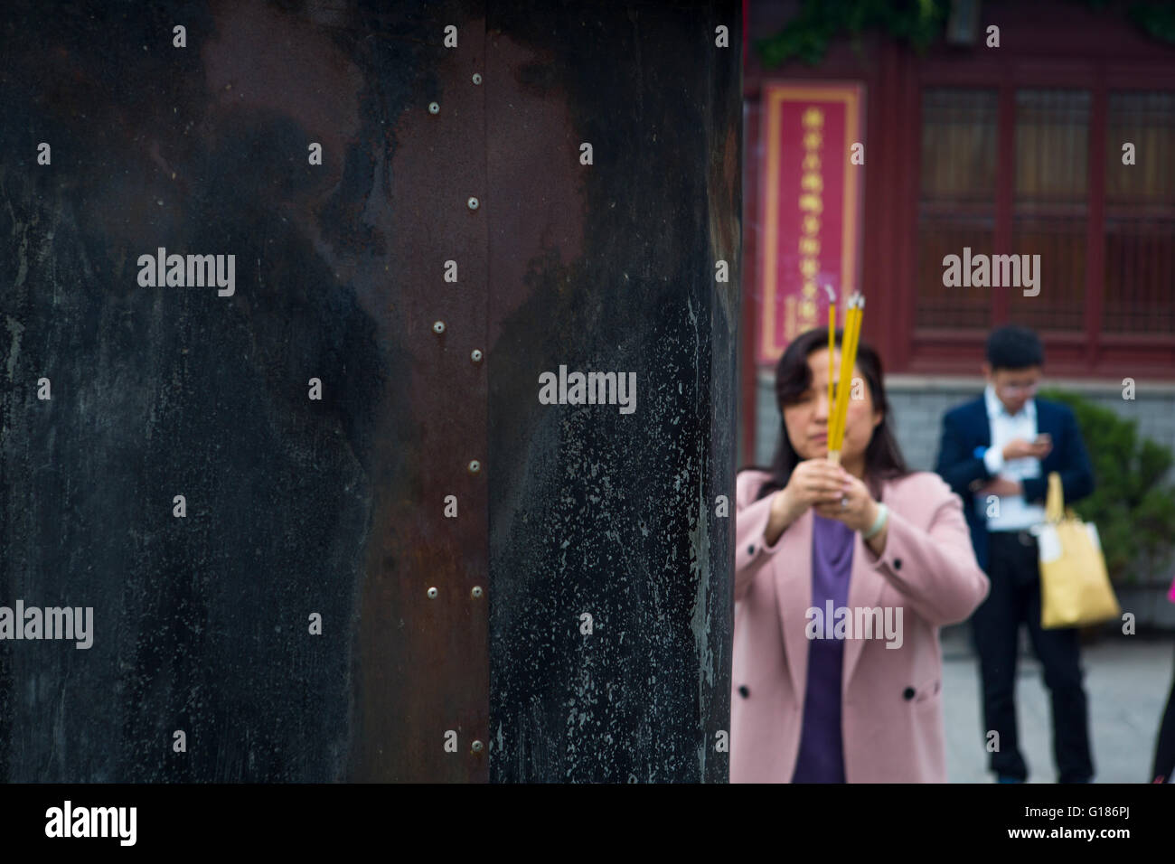 I religiosi donna cinese pregando con bastoncini di incenso a Jiming buddista di Tempio di Nanjing, la religione del Buddismo in Cina Foto Stock