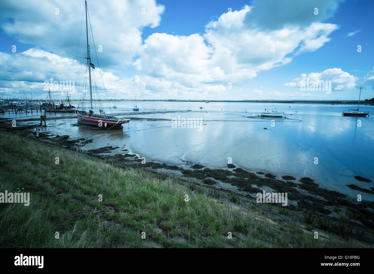 Una vecchia imbarcazione a Heybridge Basin, Essex, vicino alla riva, come la marea sta andando fuori Foto Stock