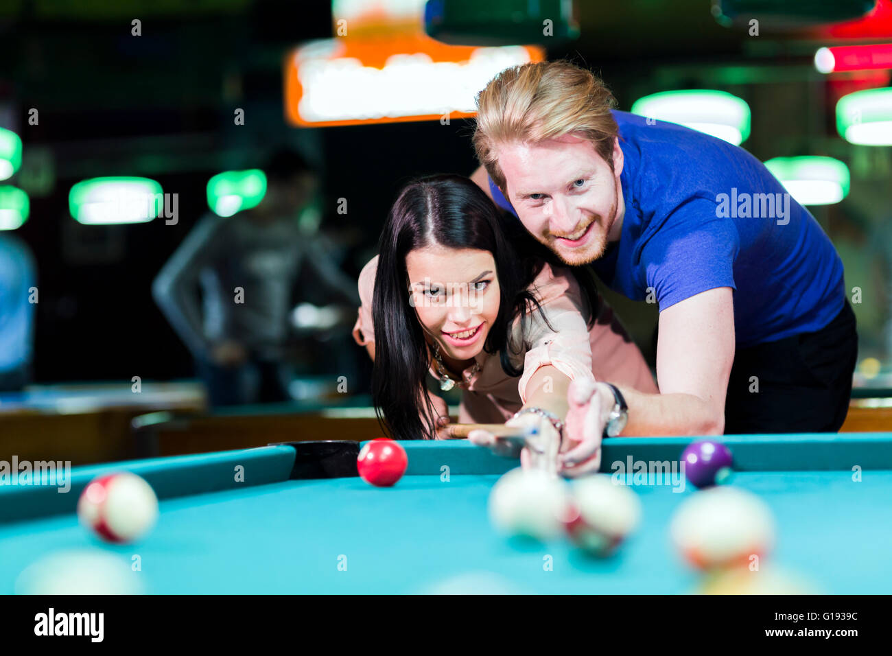 Giovane uomo bello e donna flirtare mentre giocando a biliardo Foto Stock