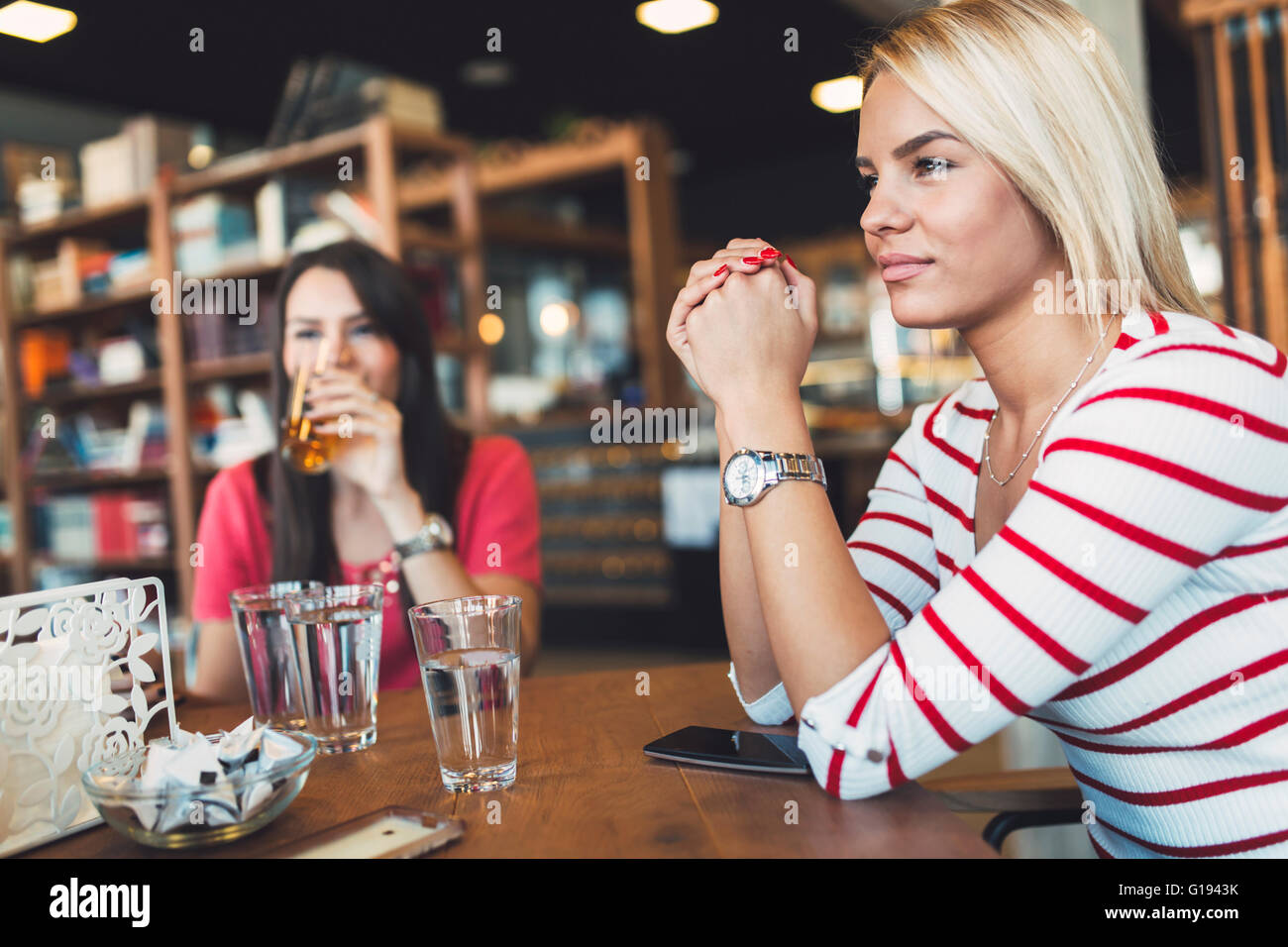 Bella donna di riposo in cafe spettegolare e parlare con gli amici Foto Stock