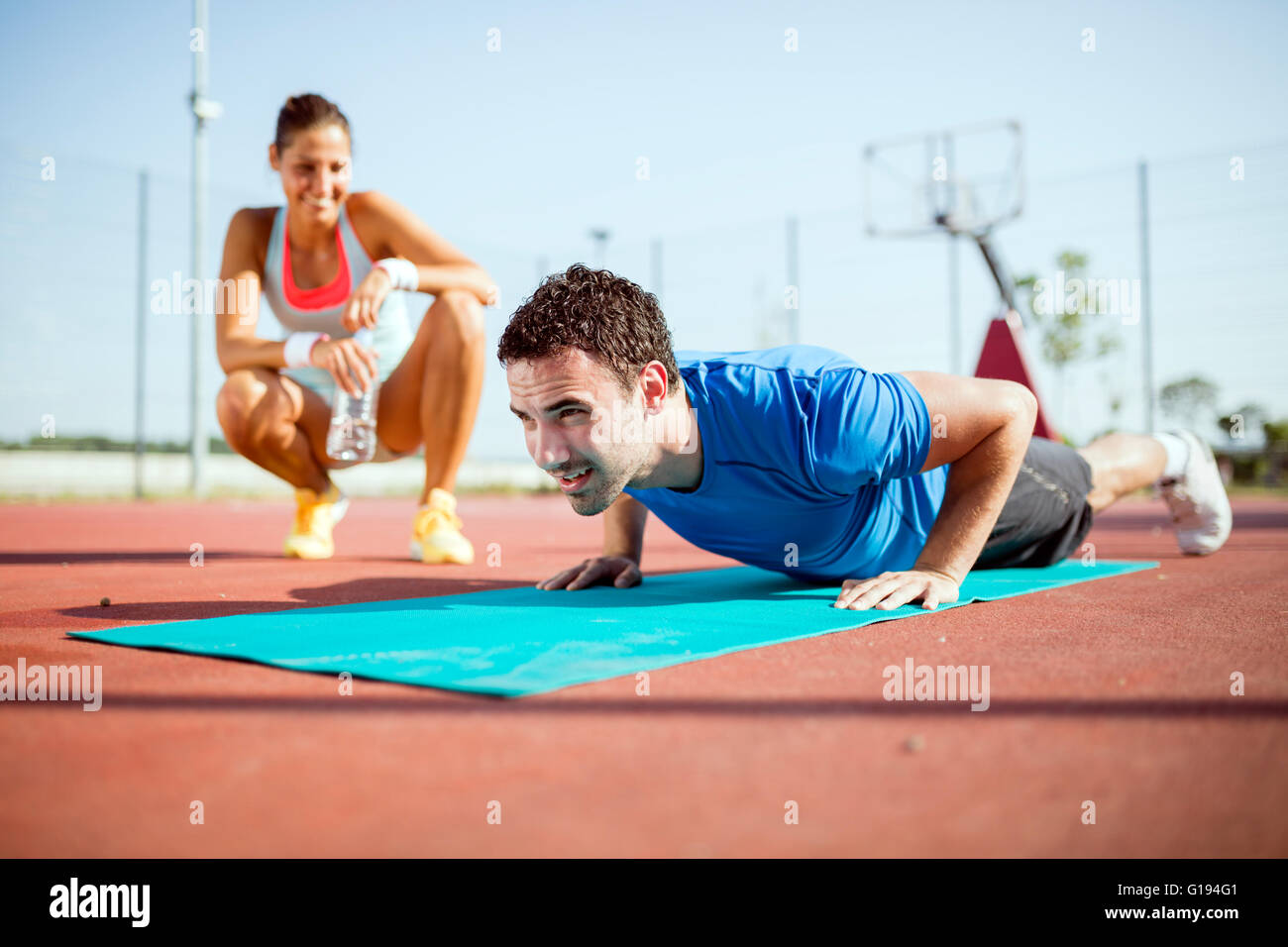 Giovane e bella, sani e personal trainer contando push-up e motivante Foto Stock