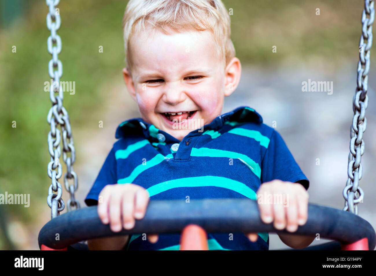 Giocoso bambino su altalena all'aperto sinceramente sorridente Foto Stock