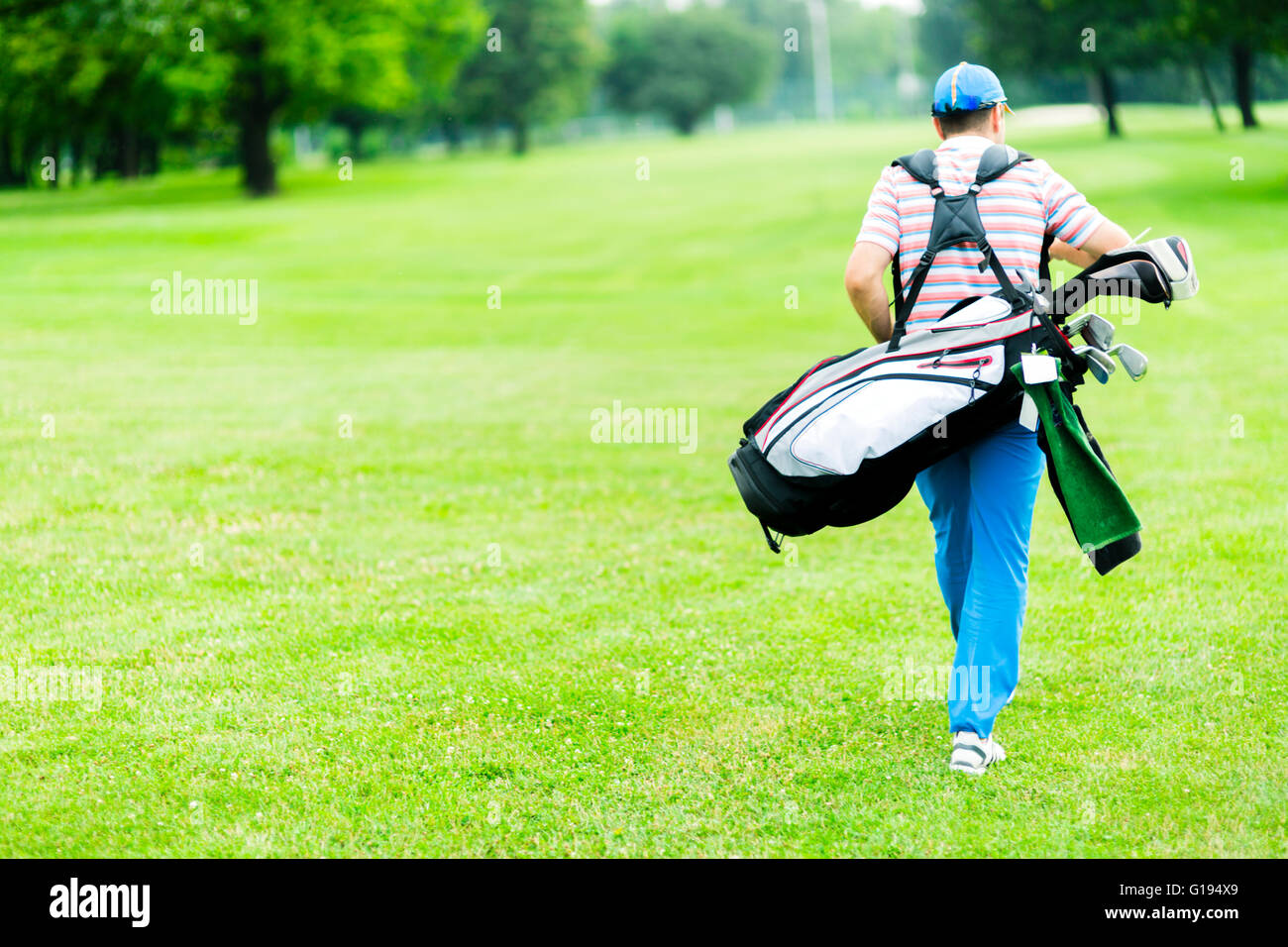 Il Golfer portando la sua apparecchiatura su una bella giornata di sole Foto Stock