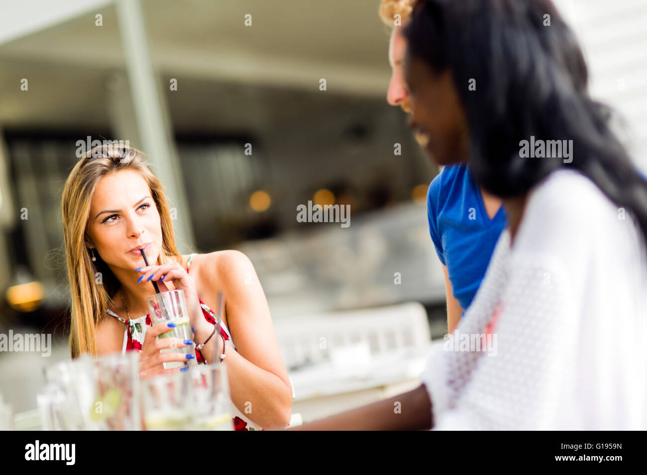 Bella donna sorseggiando attraverso una cannuccia all'aperto mentre si siede a un tavolo Foto Stock