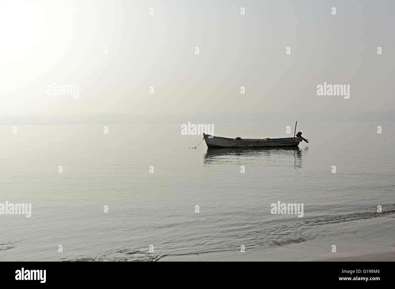 Mattinata tranquilla scena di lone tradizionale barca da pesca che sono ancorate al largo di costa dopo la notte di pesca in viaggio. Foto Stock