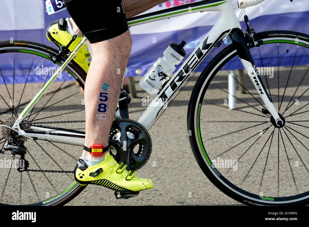 Triatleta lasciando area di transizione in bicicletta a Stratford Triathlon, Warwickshire, Regno Unito Foto Stock