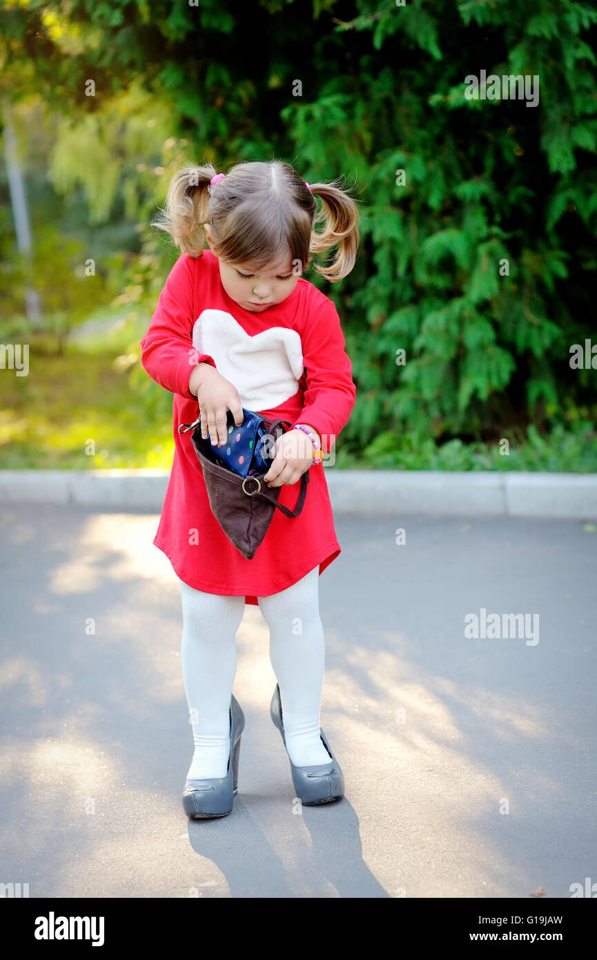 Bambina con borsetta in posizione di parcheggio Foto Stock