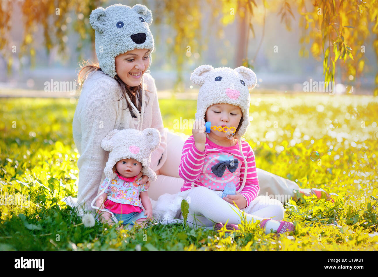 Madre e figlia in maglia cappelli orsi, con bolle di sapone Foto Stock