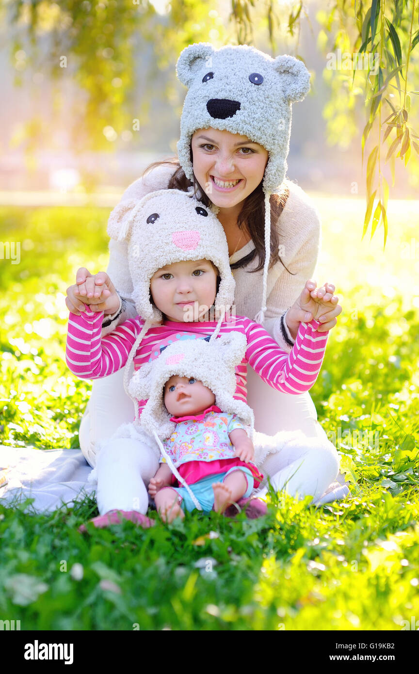 Madre e figlia in maglia cappelli poggia con una bambola Foto Stock