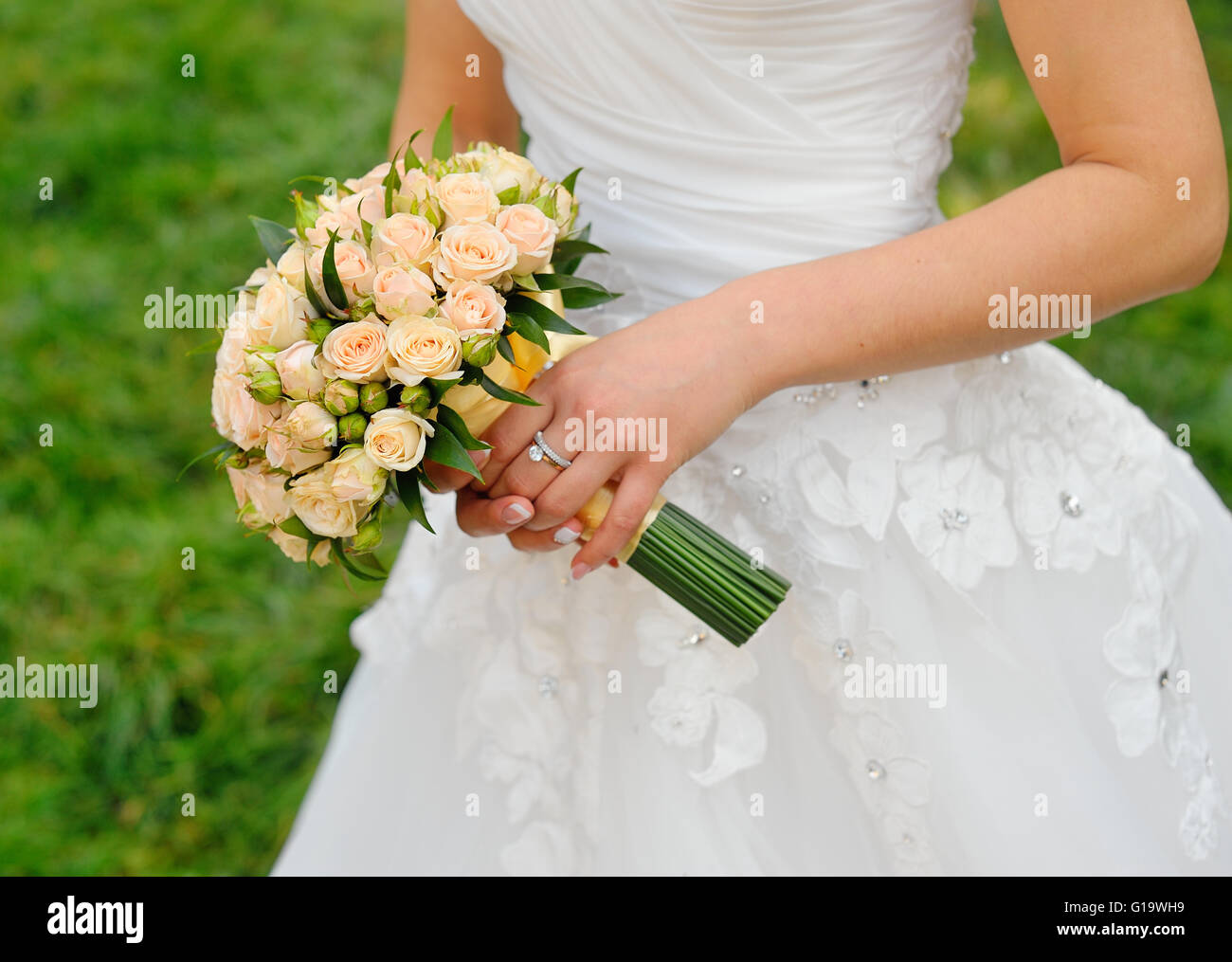 Bouquet di nozze nella mani della sposa con rose crema Foto Stock