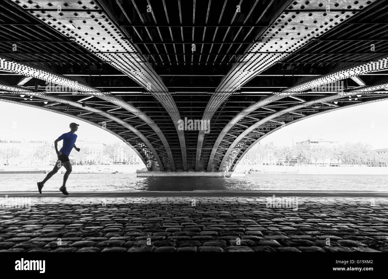 Uomo che corre sotto il Pont de l'Universite bridge a Lione in una calda giornata di primavera. Foto Stock