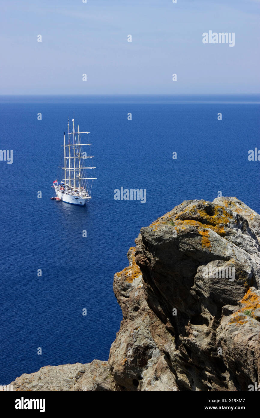 Star Clipper crociera nave ancorata nell'Egeo blu oceano nel periodo estivo di fronte da Mirina's rockycastle. Isola di Limnos Foto Stock