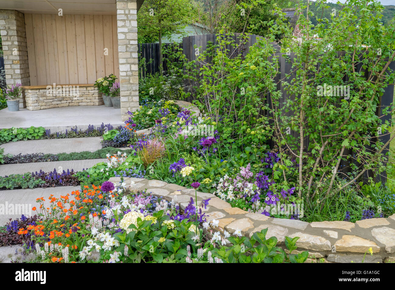 Percorso in un giardino di primavera con creativo di piantare nel percorso e di confine. Luminose fiori di primavera attirare l'occhio. Foto Stock