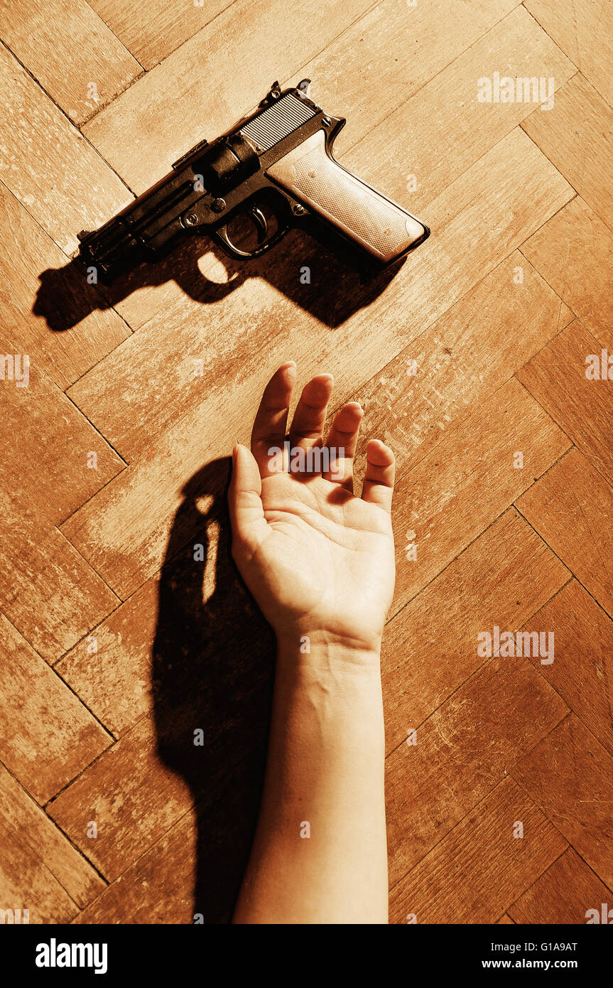 Donna mano sdraiato sul pavimento e una pistola vicino a lei Foto Stock