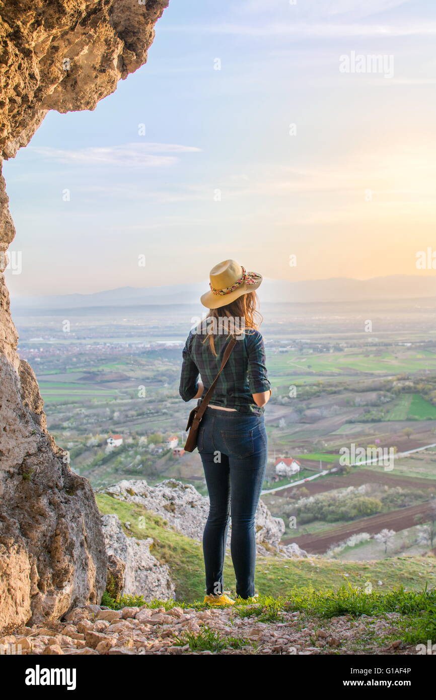 Donna che guarda al di fuori della grotta su un viaggio escursionistico Foto Stock