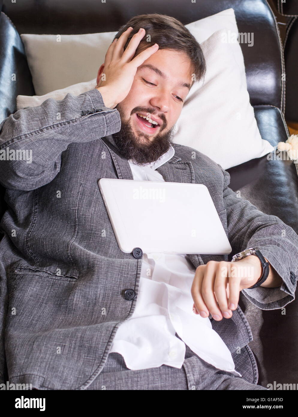 Assonnato imprenditore con un dispositivo tablet pc su un divano Foto Stock