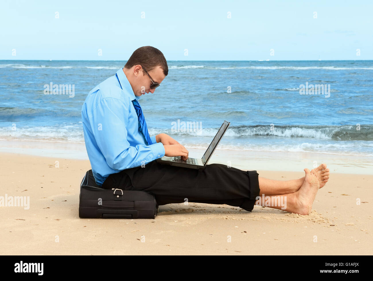 Giovane imprenditore lavora con il computer portatile sulla spiaggia Foto Stock