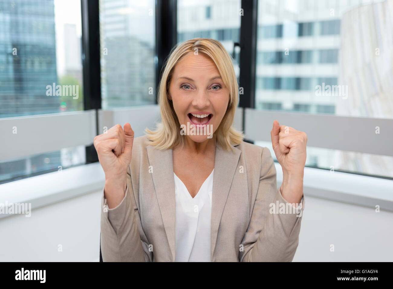Happy Business donna bracci verso l'alto. Ufficio moderno sfondo Foto Stock