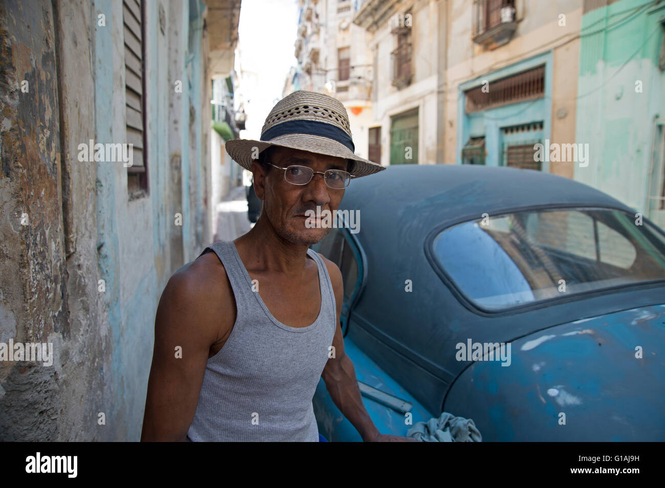Un cubano di uomo che indossa un cappello di paglia di ripristino di un vecchio 1950 classic American car nei vicoli di La Habana Vieja La Habana Cuba Foto Stock