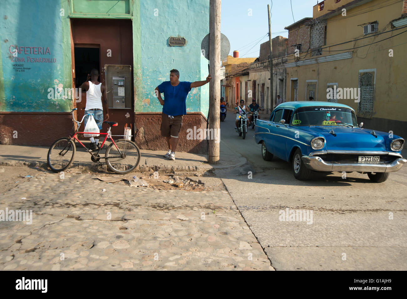 Un vecchio classico anni cinquanta la vettura americana passando un telefono pubblico coda su un angolo di strada in Trinidad, Cuba Foto Stock