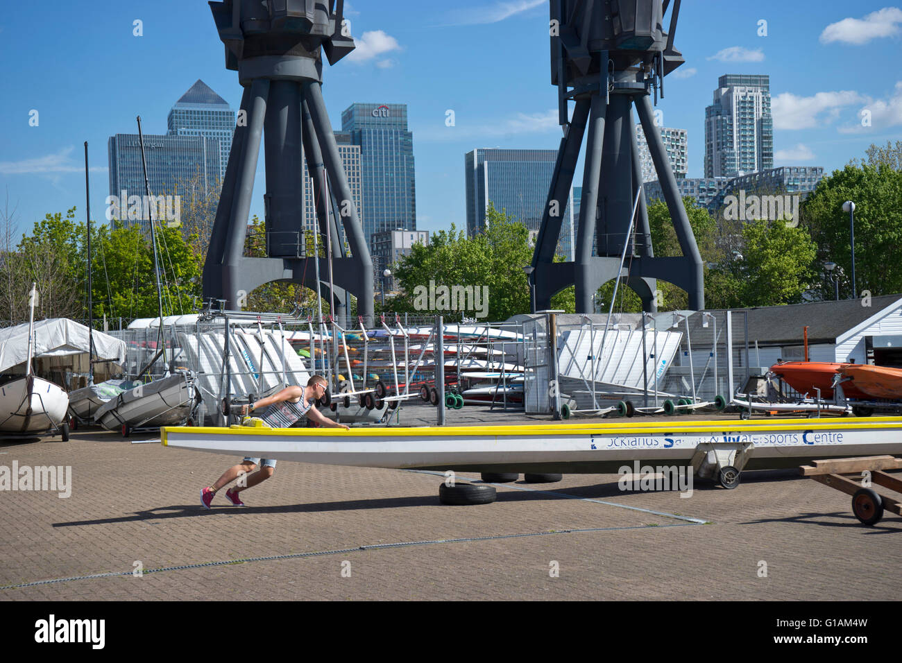 Uomo che ripara barca a vela Docklands e centro di sport acquatici nelle vicinanze del Canary Wharf di Londra, Regno Unito Foto Stock